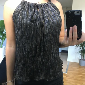 Glittertopp från Zara - Glittrig/svart topp med guld och silver i storlek xs. Använd fåtal gånger. Knytning i fram. Går även att ha den med baksidan fram om man inte vill ha knytningen fram (se sista bilden). Kan mötas upp i Skövde eller Hjo. Skickas mot fraktkostnad.