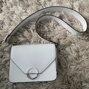 Vit axelbandsväska  - Vit axelbandsväska med avtagbart band. Magnet när man stänger den. Knappt använd, inga märken. Frakt är ca 66kr.                                                                                      Skriv gärna om du vill se flera bilder, priset kan diskuteras!