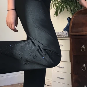 Svarta kostymbyxor - Kostymbyxor från Twilfit med brodering och paljett- detaljer på höften och ena byxbenet. Perfekt rak passform och super fint skick. Sitter på mig som är 36. Skulle säga att de passar 34 - liten 36a. Jag är 170 cm Hör av er om ni har frågor. Möts på södermalm 💞💞💞