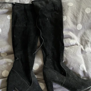 Höga  stövlar  - Höga overknee-stövlar med snörning bak. Använda fåtal gånger. I något mocka-aktigt tyg. Lite dammiga då dom legat länge men i övrigt fint skick. Sköna att gå i.