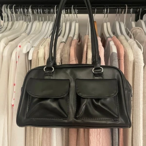 Svart axelväska med fickor - Snygg svart axelväska i syntetmaterial med två stora framfickor och dragkedja upptill. 💕🍓 Väskan har dubbla handtag för bekväm användning.🍒🌸 öppen för prisförslag!!