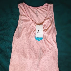 Rosa linnetopp från SOC - Säljer en rosa linnetopp från SOC i ett lätt och luftigt material. Toppen har en öppen rygg och är perfekt för varma dagar eller träning. Den är ärmlös och har en enkel design som gör den lätt att matcha med andra plagg.