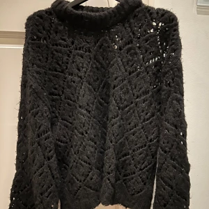 Svart stickad tröja från Zara - Säljer en svart stickad tröja från Zara med ett hålmönster. Tröjan har en hög krage och långa ärmar. Storlek L så lite oversized. 