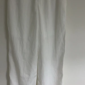 Vita linnebyxor - Snygga vita linnebyxor med en avslappnad passform. Perfekta för varma sommardagar med sitt lätta och luftiga material. Byxorna har en klassisk design som passar till många olika stilar. De är dock genomskinliga och de har en skjorta till som tillhör den för den kom i en sett.( finns för att köpa)