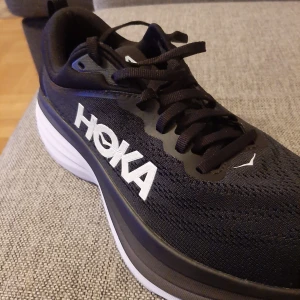  Hoka bondi 8  - Snygga och bekväma svarta sneakers från Hoka med vit sula och snörning. Perfekta för löpning eller vardagsbruk. Helt nya aldrig använda, små o storleken 