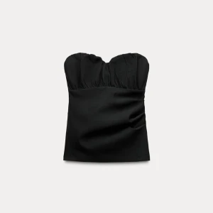 Svart axelbandslös topp - Snygg svart axelbandslös topp med en elegant och stilren design. Perfekt för en kväll ute eller en speciell tillställning. Toppen har en smickrande passform och är lätt att matcha med olika outfits.