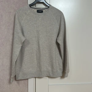 Ljusgrå tröja från Hampton Republic - Säljer en stilren ljusgrå tröja från Hampton Republic. Tröjan har långa ärmar och en rund halsringning. Perfekt för en avslappnad stil.