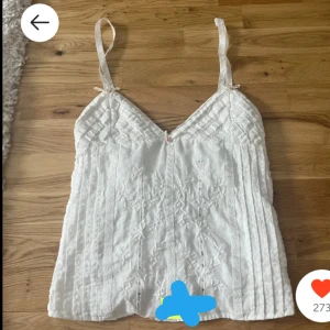 Vit broderad linnetopp - Säljer en söt vit linnetopp med broderade detaljer och smala axelband. Perfekt för varma sommardagar. 