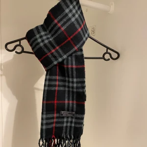 Burberry - Säljer nu denna Snygga halsduk från Burberry i blått. Tillverkad i mjukt lammull med klassiskt fransad kant. Perfekt för att hålla dig varm och stilren under kyliga dagar. Hör av er vid funderingar☺️