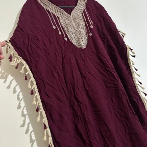 Vinröd klänning  med dekorativa detaljer - Elegant vinröd kläning anvånd 2-3 gånger. Skulle säga passar L-xl och även mindre då den är luftig och skön