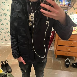 Field jacka från J.Lindeberg - Snygg field jacka från J.Lindeberg med dragkedja och knappar. Perfekt för kyligare dagar med sin stilrena design och praktiska fickor. Jackan har långa ärmar och en hög krage för extra skydd mot väder och vind. Saknas 2 knappar därav priset!