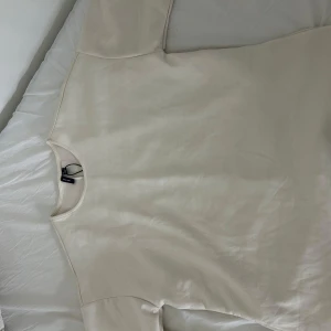 Beige tröja från Vero Moda - Säljer en stilren beige tröja från Vero Moda. Perfekt för en minimalistisk look. Tröjan har en enkel design med rund hals och korta ärmar. Perfekt till vardag och fest. På riktigt aldrig använd 