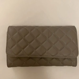 Grå axelväska  - Snygg grå axelväska med quiltat mönster och kedjedetaljer på axelremmen. Perfekt för att ge en stilren touch till din outfit. Don Donna är märket och väskan är så snygg och elegant! Ett roligt bra skick och använd endast eyt fåtal gånger! 