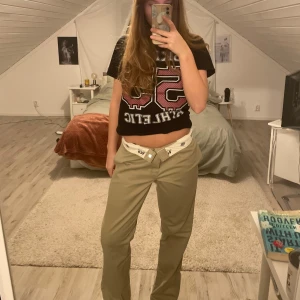 Beige byxor med bälte - Snygga beige byxor från dickies. Byxorna har en rak passform och är perfekta för en avslappnad stil. De är midwaist och passar bra till olika tillfällen.