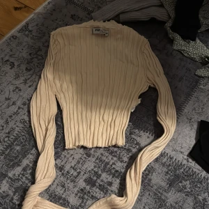 Beige ribbad tröja från new yorker - Säljer en beige ribbad tröja från Fila med långa ärmar och en croppad design. Perfekt för en stilren och bekväm look. Passar bra till både jeans och kjol.