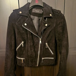 Skinnjacka - Gjord av äkta läder, mockakänsla.  Använd två gånger då jag köpte den för liten, skulle säga att den är mer som en XS än S. Den är svart men tyvärr dåligt återgiven på bild. Nyskick helt utan skavanker.