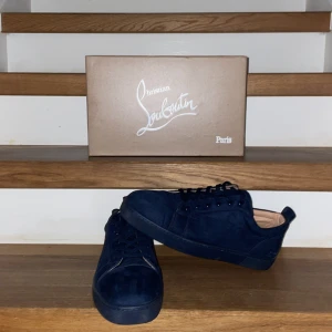 Louboutin skor - Snygga mörkblåa sneakers från Christian Louboutin i mocka med den ikoniska röda sulan. Skorna är i perfekt skick och en stilren design som passar perfekt för en trendig look. Skorna är använda endast ett fåtal gånger. Tveka inte för minsta fråga!