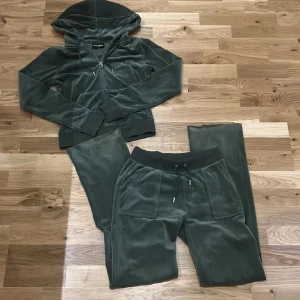 Grön velour hoodie och byxor från Juicy Couture - Säljer en grön velour hoodie och matchande byxor från Juicy Couture. Hoodien har dragkedja och snörning i luvan och byxorna har snörning i midjan. Settet är som nytt men säljer pga för litet och de kommer tyvärr inte till användning!