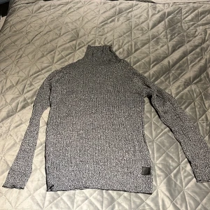 Grå stickad polotröja - Snygg grå stickad polotröja med lång ärm och ribbade detaljer. Perfekt för kyliga dagar och ger en stilren look.