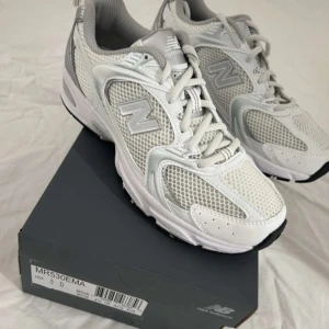 Vita sneakers från New Balance - Snygga vita New Balance sneakers med grå detaljer och snörning. Skorna har en bekväm passform och en slitstark sula, perfekt för vardagsbruk. De är tillverkade i syntetmaterial med mesh för extra andningsförmåga. Missade returdagen och är därför aldrig använda!