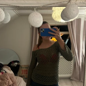 Grön offshoulder tröja - Snygg grön offshoulder tröja med ett genombrutet mönster. Perfekt för en avslappnad stil med en touch av elegans. Tröjan har långa ärmar och en bekväm passform.