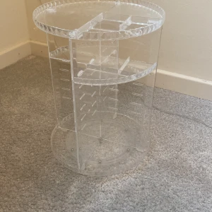 Roterande smyckesställ  - Praktiskt och stilrent roterande smyckesställ i transparent akryl. Perfekt för att organisera smink eller liknande. Stället har flera nivåer för att produkter ska kunna organiseras. De är en liten spricka i boten men inget man tänker på eller något som påverkas🩷