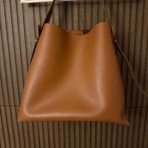 Brun axelväska mango - Snygg brun axelväska i skinn med minimalistisk design. Väskan har en justerbar axelrem och en stilren form som passar perfekt för vardagsbruk. Enkel att matcha med olika outfits. 