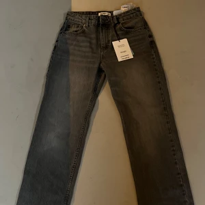 Grå jeans från Pull&Bear - Snygga grå jeans från Pull&Bear i straight modell. De har en klassisk design med fem fickor och knappgylf. Perfekta för en avslappnad stil. Storlek 36.