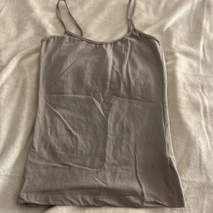 Beige linnetopp från Åhlens - Säljer ett beiget linne från Åhlens Woman i storlek S. Toppen har smala axelband och är tillverkad i ett mjukt material som passar perfekt för varma dagar. Enkelt och snyggt basplagg för din garderob.