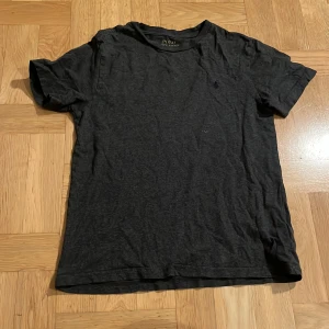 Mörkgrå t-shirt från Polo Ralph Lauren - Snygg mörkgrå t-shirt från Polo Ralph Lauren. Perfekt för en avslappnad stil med sin klassiska design och diskreta logga på bröstet. Gjord i mjukt material för extra komfort.