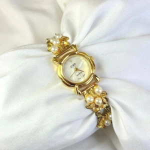 Vintage pärlklocka (otickande)  - Elegant guldfärgad klocka från Calypso Studios med pärlor och blom design på armbandet. Klockan har en vit urtavla med guldfärgade visare. Säljer för att den var för stor för mig :) 