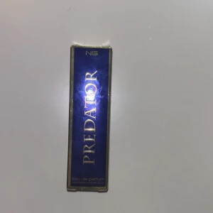 Predator Eau de Parfum från NG - Upptäck Predator Eau de Parfum från NG, en doft med en kraftfull och förförisk karaktär. Flaskan är elegant och rektangulär med en gyllene spraypump. Perfekt för den som vill göra ett starkt intryck.