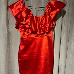 Röd klänning, S, supersnygg - Snygg röd klänning från Shein i stetchigt, glansigt material med volangdetaljer vid axlarna. Perfekt för en festlig kväll. Klänningen har en dragkedja i ryggen för enkel påklädning. Väldigt smickrande på!