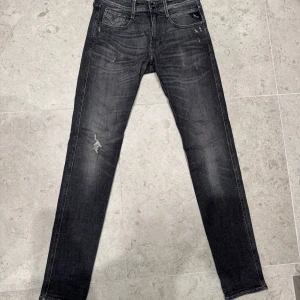 Svartgråa Replay jeans med trendiga slitningar. - Säljer nu dessa Replay jeans som är storlek W29 L 34. Dem är mörka med slitningar för en trendig look. Skicket är 9/10 så de är inte använda så mycket och har samt ingen skada. De är perfekt för dessa vinter dagar. Hör gärna av dig vid funderingar.