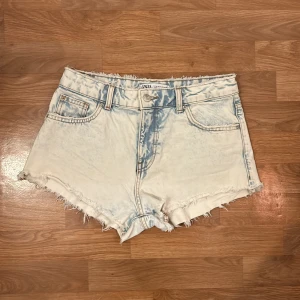 Ljusa jeansshorts från Zara - Snygga ljusa jeansshorts från Zara med fransiga kanter och en cool tvättad look. Perfekta för sommardagar! De har klassisk femficksdesign och knappgylf. Inga fläckar eller slitage. . 