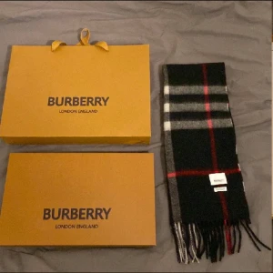 Rutig halsduk från Burberry - Snygg och klassisk rutig halsduk från Burberry i svart, grått, vitt och rött. Perfekt accessoar för att hålla dig varm och stilren under kyliga dagar. Kommer med originalförpackning och kvitto. Tveka inte med att ställa frågor👍✅ pris går att diskuteras!!