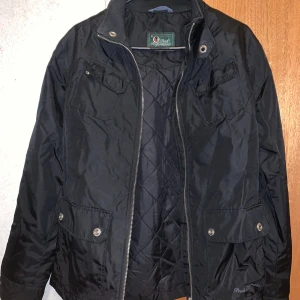 Svart jacka från Peak Performance - Snygg svart jacka från Peak Performance med dragkedja och knappar. Jackan har en quiltad insida och praktiska fickor framtill. Den är i bra skick.