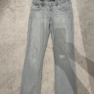 Grå jeansbyxor - Snygga grå jeansbyxor med en klassisk design. De har en knapp och dragkedja framtill samt fem fickor. Perfekta för en avslappnad stil.