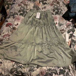 Grön kjol från Vila - Snygg grön kjol från Vila i en luftig och flödande design. Kjolen har en elastisk midja och flera volanger som ger en fin rörelse. Perfekt för att skapa en avslappnad och stilren look.