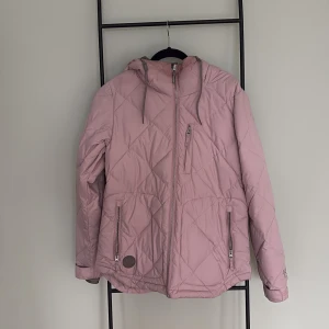 Rosa snowboardjacka från Nitro - Rosa quiltad snowboardjacka från Nitro. Jackan har flera praktiska fickor och snölås.  Perfekt för kyligare dagar i backen. Använd ett fåtal gånger. Pris kan diskuteras vid snabb affär!