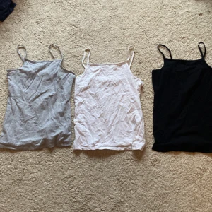 Tre linnen från H&M i olika färger - Säljer tre linnen från H&M i storlek 146/152. Färgerna är grå, vit och svart. Perfekta basplagg med smala axelband💕Du får alla 3 för 120kr💕
