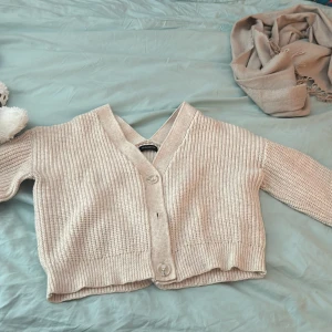 Beige stickad kofta från Even&Odd - Säljer en mysig beige stickad kofta från Even&Odd. Koftan har en v-ringad design med stora knappar framtill och långa ärmar. Perfekt för kyliga dagar!