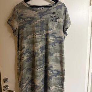 Camouflage t-shirt från Charlotte Russe - Säljer en cool camouflage t-shirt från Charlotte Russe i storlek XL. T-shirten har ett slitet mönster på framsidan och korta ärmar. Perfekt för en avslappnad stil.