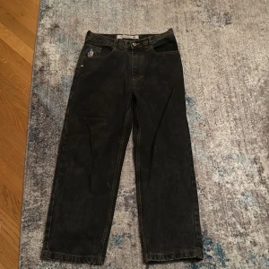 Svarta polar 93 - Coola svarta polar 93 jeans med en unik broderad detalj på fickan och en gul patch med '93!' på baksidan. Jeansen har en straight passform och är perfekta för en avslappnad stil. Ganska nya men ett litet hål under den högra fickan. Storlek 28/30