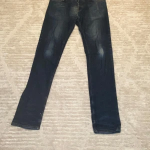 Blå jeansbyxor från Celemente - Snygga blå jeansbyxor från Celemente med klassisk femficksdesign och en broderad detalj på bakfickan. Byxorna har en rak passform och är perfekta för en avslappnad stil. Märkesdetaljer syns på både fram- och baksidan.