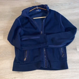 Mörkblå cardigan från PRL - Säljer en snygg mörkblå jacka från Polo Ralph Lauren. Jackan har dragkedja framtill och praktiska fickor med dragkedjor. Perfekt för höst och vår med sin stilrena design och bekväma passform. [storlek liten M][skick 8/10]