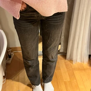 Svarta jeans från Zara - Snygga svarta jeans från Zara med en klassisk straight fit. De har en knapp och dragkedja framtill och är perfekta för en avslappnad stil. Jeansen har en rå kant vid bensluten för en trendig look. Lite korta på mig som är 168cm. De är mid waist och lite åt stentvättad färg. Jag har sytt in benen för att de ska bli straight annars om sömmen tas upp liknar de en mer wide modell. Pris går att diskutera.