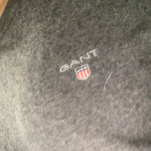 Grå tröja från GANT - (HÄRR TRÖJA) Säljer en stilren grå tröja från GANT med broderad logotyp på bröstet. Tröjan har långa ärmar och en klassisk rund halsringning. Perfekt för en avslappnad och snygg look.