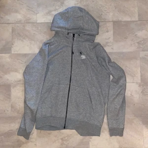 Grå huvtröja från Nike - Säljer min killes gamla zipup från Nike då den inte längre passar. Har själv använt den så är inte gjord för något specifikt kön. 