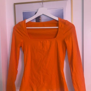Orange r topp - Snygg orange topp med långärmad design och fyrkantig halsringning. Perfekt för att liva upp garderoben med en färgklick.